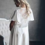 A bride wearing a white satin wedding robe Kalmer with lace back by rara avis