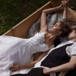 a bride wearing wedding dress and a groom lying on a wooden boat