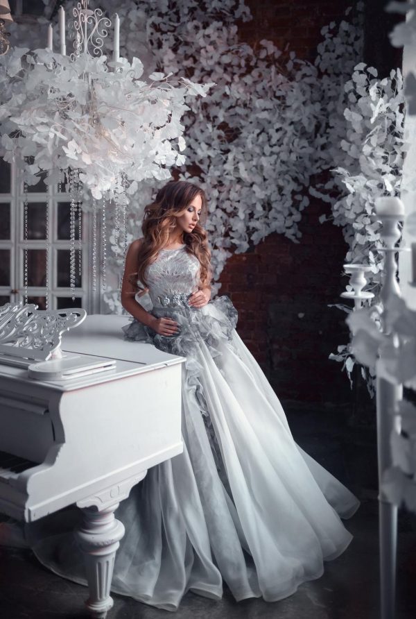 bride leaning on the piano in her purple colour wedding gown Lavin from Rara Avis with basque ruffle skirt, image 1
