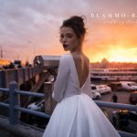 A bride wearing satin princess wedding dress Tilda by blammo-biamo with long sleeves, long train and open back with brooch, image 1