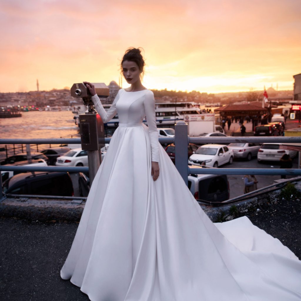 A bride wearing satin princess wedding dress with bodice decorated with two embroidered elements.