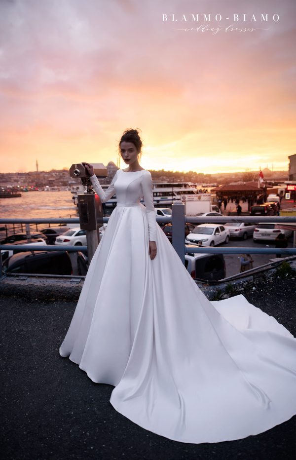 A bride wearing satin princess wedding dress Tilda by blammo-biamo with long sleeves, long train and open back with brooch, image 3