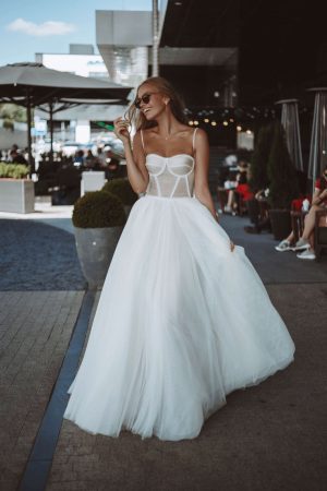 A-line off-white wedding dress with the tulle skirt and fitted bodice with the sweetheart neckline and pearls decorations