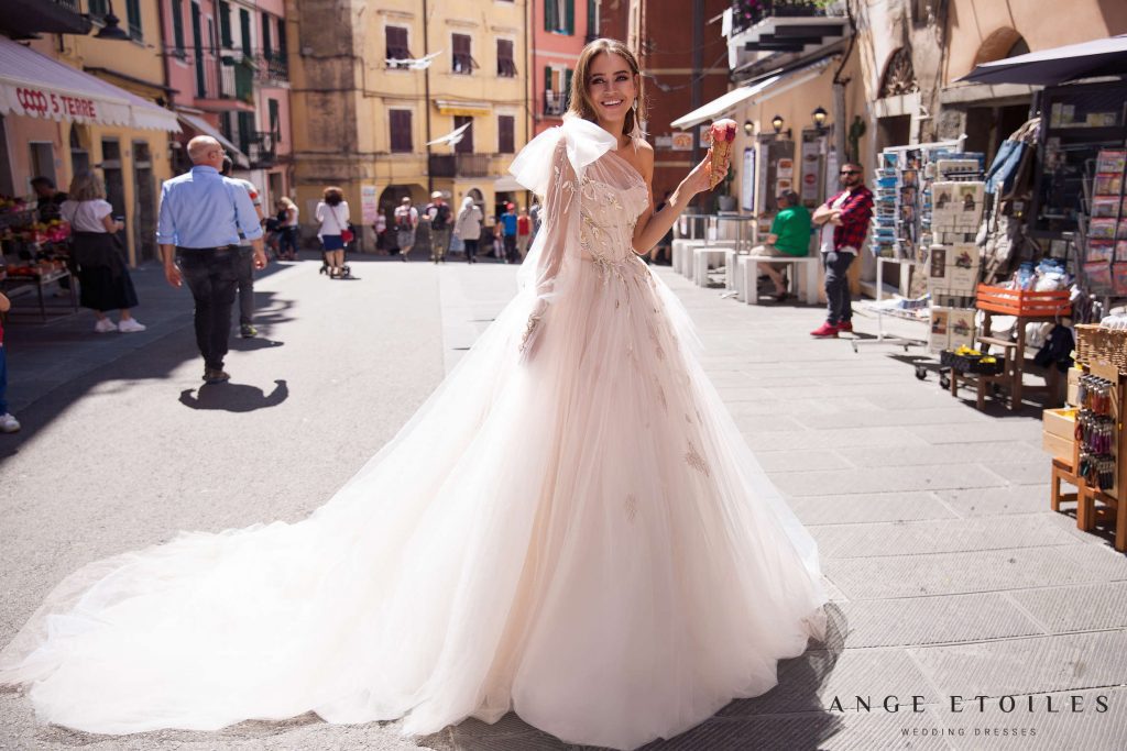 Princess style blush wedding dress Gretta with a bow on one shoulder designed Ange Etoiles